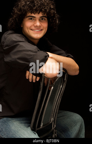 Teenage boy (16-17) sitting backwards on chair, portrait Stock Photo