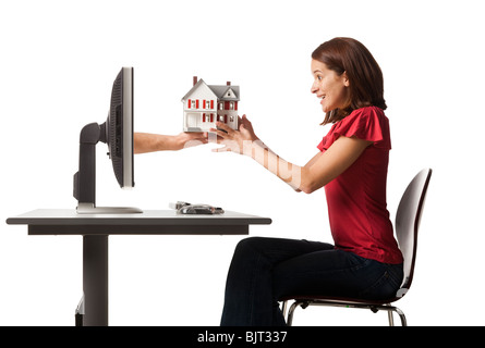 Conceptual picture of young woman receiving house out of her computer Stock Photo