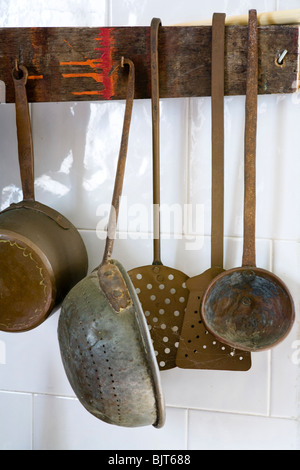 Old kitchen pots and pans hanging on wall in Italy Stock Photo