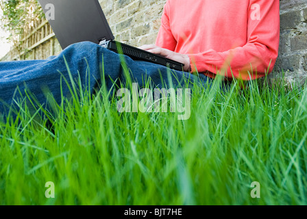 Person using laptop in garden Stock Photo