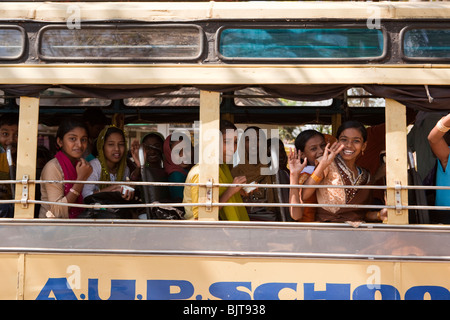 India, Kerala, Palakkad, smiling senior school girl students waving from bus window Stock Photo