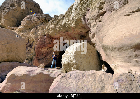 A woman standing near entrance to a cave Stock Photo