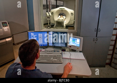 Seated at a control console, a medical technician prepares for a CT examination at a California radiology clinic. Stock Photo