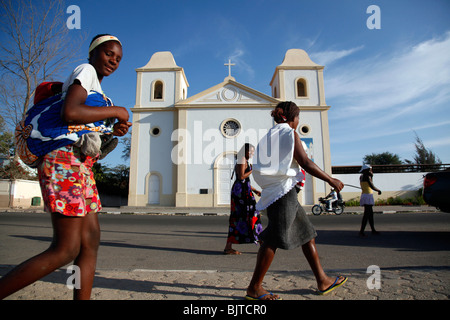 Women carrying their children past a church in the bay of Namibe, Namibe Province, Angola, Africa Stock Photo