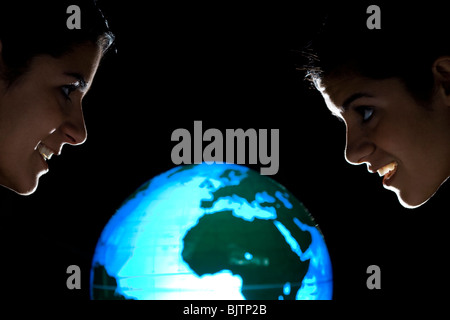 Sisters studying earth globe Stock Photo