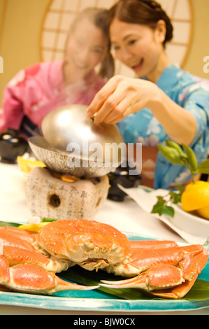 Women dressed in yukatas sitting down to eat a meal Stock Photo