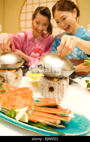 Women dressed in yukatas sitting down to eat a meal Stock Photo