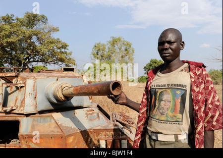 South Sudan, Rumbek , wreck of armoured car FV601 Saladin, captured by SPLA from SAF during civil war, man with T-Shirt former SPLA leader John Garang Stock Photo