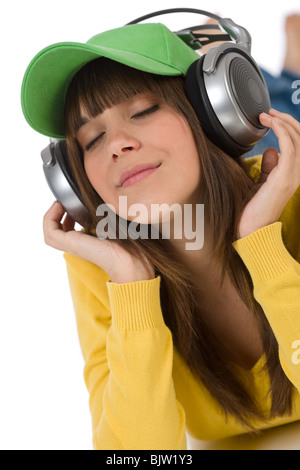Happy female teenager enjoy music on white background, with headphones and baseball cap Stock Photo