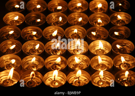 Many tealights candles lit at night flame detail Stock Photo