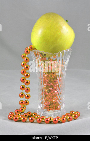 green apple in vase, golden beads, still life. table top composition, artistic arrangement Stock Photo