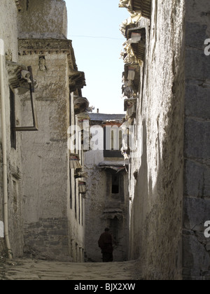 A Buddhist monk walks down the alley between two buildings at the Drepung Monastery in Lhasa, Tibet Stock Photo