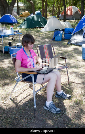 Woman using a laptop computer in a campsite Texas USA Stock Photo