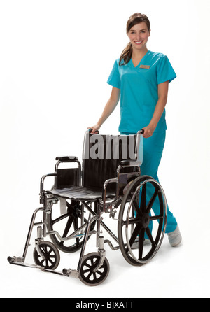 Studio photo of female health care worker standing beside wheelchair. White background. Stock Photo