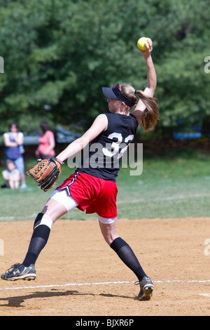 High kicking girls high school softball pitcher. Stock Photo