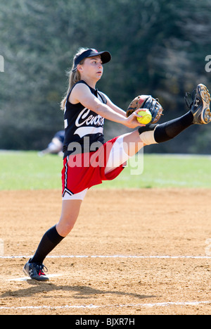 High kicking girls high school softball pitcher. Stock Photo