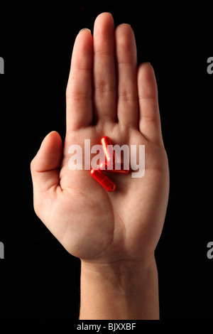 A female woman's hand holding three pills in the palm of her hand Stock Photo