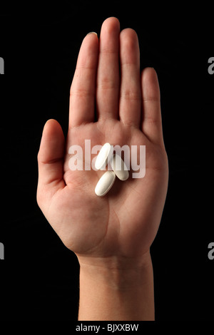 A female woman's hand holding three pills in the palm of her hand Stock Photo
