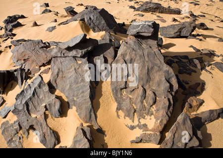 Black rocks in desert floor within the Gilf Kebir National Park, Western Desert, Egypt Stock Photo