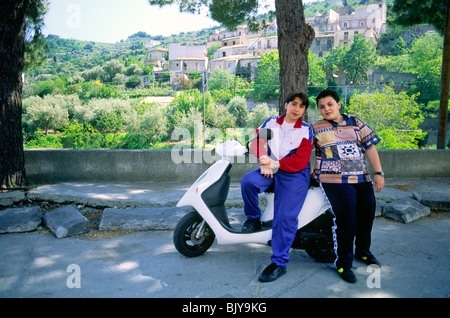 Sicily, Italy. Two local teenage friends boys young men pose for camera with scooter moped in the mountain town of Randazzo Stock Photo