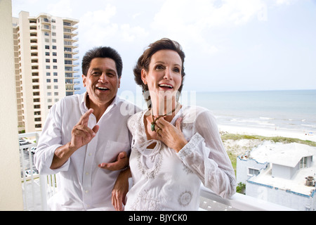 Middle-aged couple standing on balcony of beachfront condo Stock Photo
