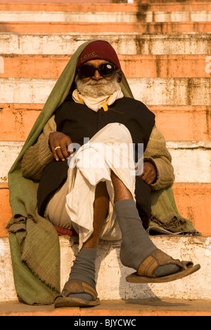An Indian man wears a woolly hat and sun glasses on the ghats in Varanasi, India. Stock Photo