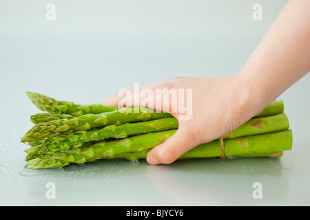 Hand of a woman holding a bunch of asparagus Stock Photo