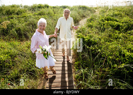 Senior couple taking a stroll along a boardwalk at the beach Stock Photo