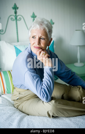 Contemplative senior woman on bed Stock Photo