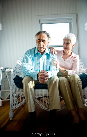 Pensive senior couple sitting side by side on wicker sofa Stock Photo