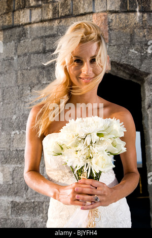 Smiling young bride holding bouquet outdoors Stock Photo