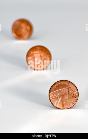 Three one penny pieces in diagonal line against a white background with the 2nd and 3rd coins out of focus Stock Photo