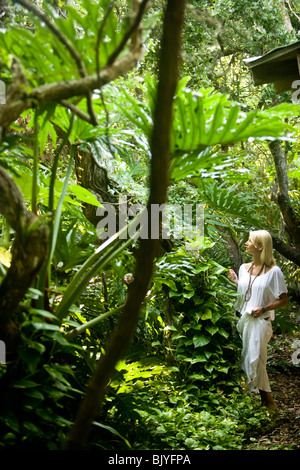 Young blonde woman in white walking through lush landscape Stock Photo