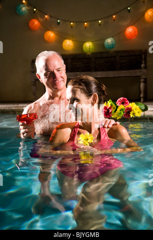 Mature couple relaxing in pool at night Stock Photo