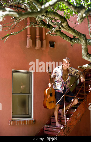Hispanic man standing on staircase with guitar outdoors Stock Photo