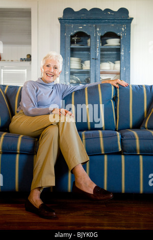 Portrait of senior woman sitting on blue striped couch Stock Photo