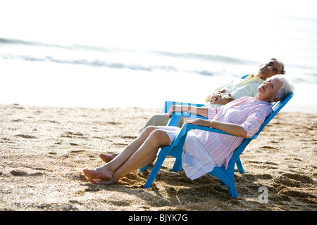 Senior couple snoozing in chairs at the beach Stock Photo