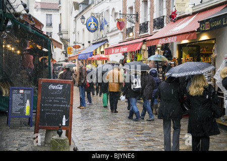 People walking under the snow in Rue Norvin, Montmartre neighbourhood in Paris, France. Stock Photo