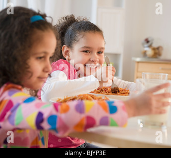 Hispanic sisters eating spaghetti Stock Photo