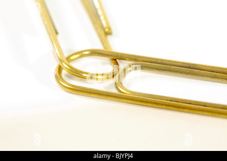 Gold paperclips linked against white background Stock Photo