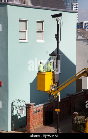 Street furniture maintenance workers using a cherry picker van to maintain street lights. Stock Photo