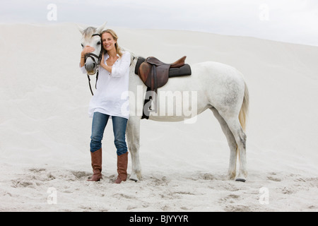 Blonde woman with horse on the beach Stock Photo