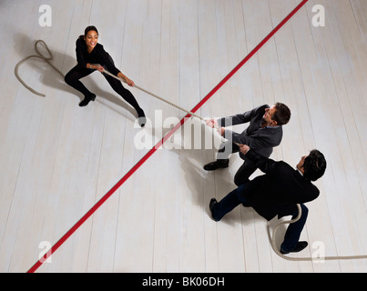 Business men pulling woman with rope Stock Photo