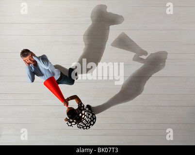 Woman shouting at man with mega phone Stock Photo