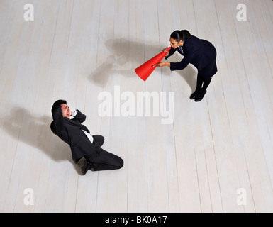 Business woman shouting at man on floor Stock Photo