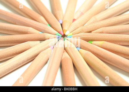 Pencil crayons in an array of colours arranged in an attractive inwardly pointing pattern on a white background. Stock Photo