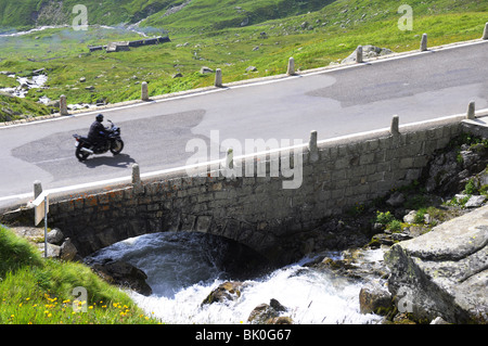 Biker on bridge over Alpine spring