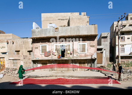 Man and woman drying a red silk fabric. Nagaur. Rajasthan. India Stock Photo