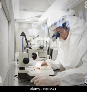 Middle Eastern scientist in clean suit using microscope Stock Photo