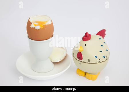 Chicken egg timer with an open soft boiled egg in an egg cup on a white background Stock Photo